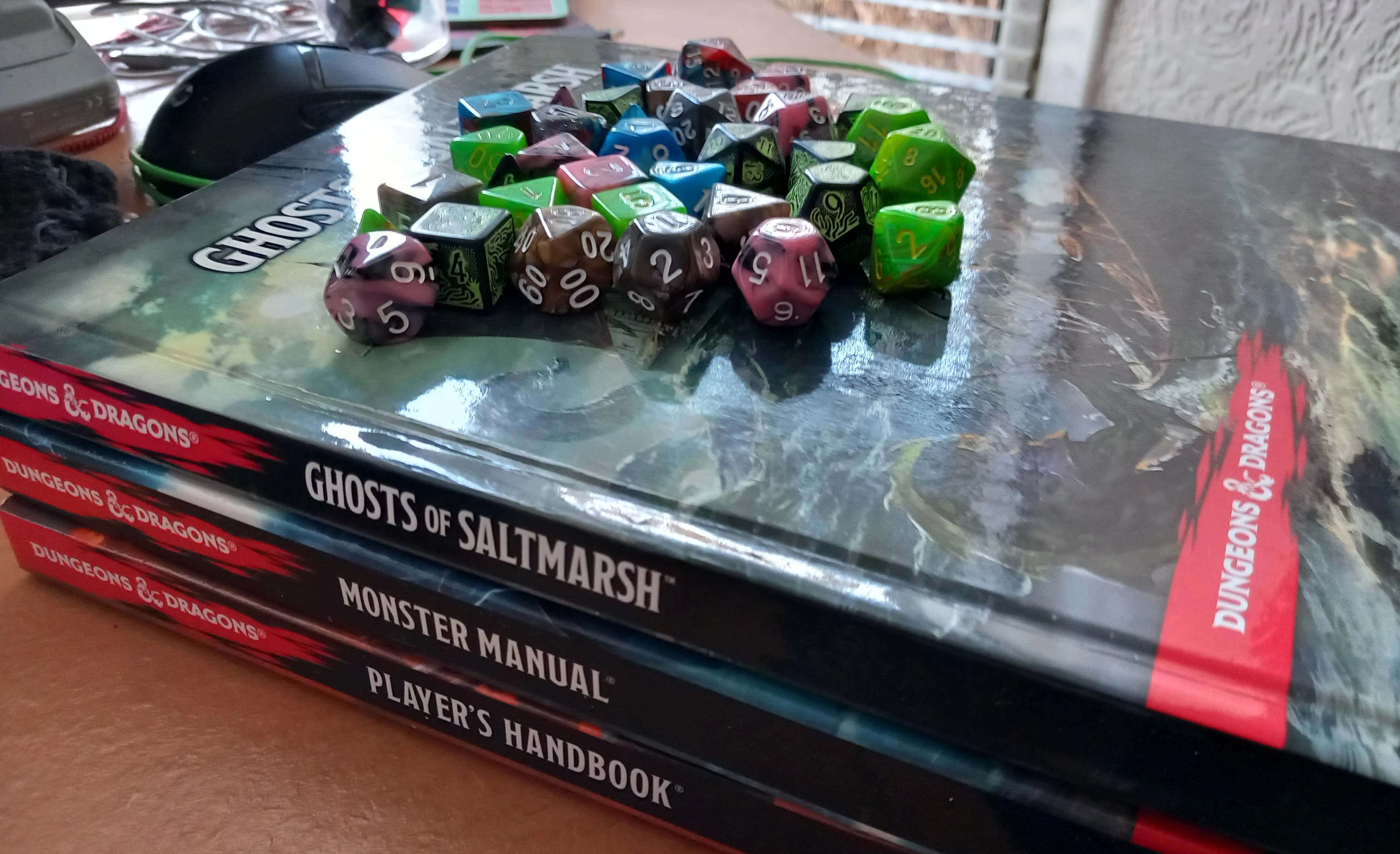 A page image of three DnD 5e books: Player's Handbook, Monster Manual, and Ghosts of Saltmarsh, topped with DnD 5e dice